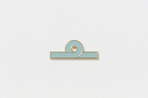 A rectangular light blue pin with gold edges and one upward loop in the design in the center