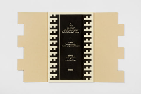 An open manila cover with a black and cream book inside with a geometric edge design and cream text on the cover