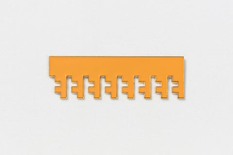 a rectangular orange pin with gold edges and Greek key designs descending